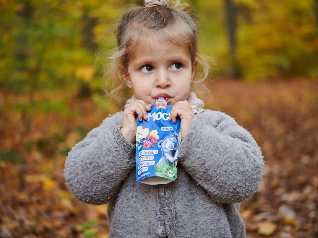 Kind trinkt Quetschie im Wald